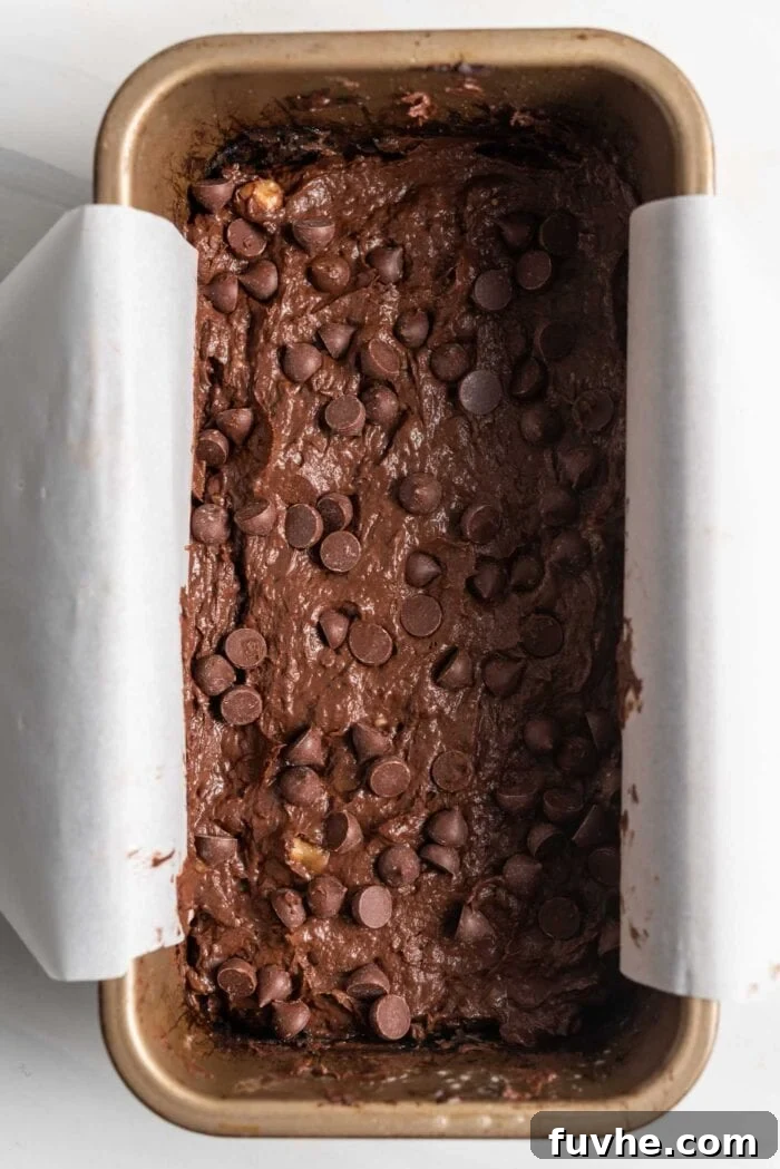 Plant-Powered Protein Brownies 6 Raw chocolate chip brownie batter spread evenly in a parchment-lined loaf pan.