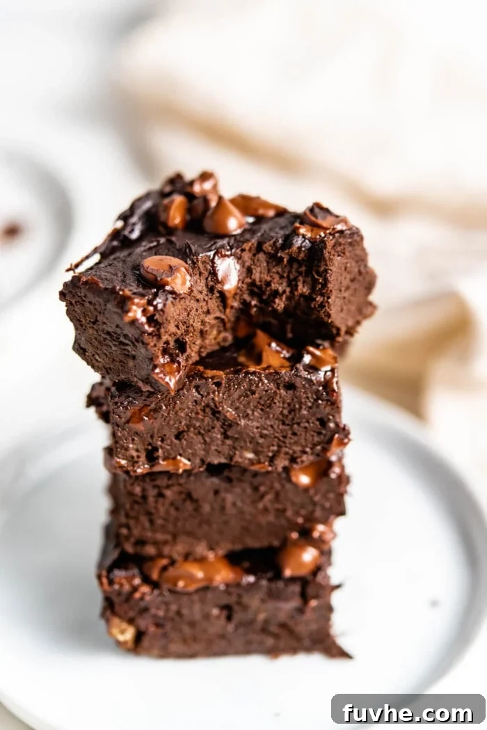Plant-Powered Protein Brownies 8 Stack of 4 chocolate brownies with one on top, showing a bite taken out, revealing the fudgy interior.