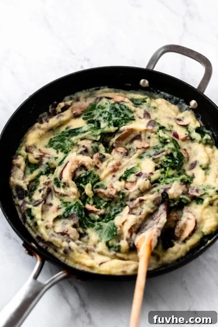 Mashed cauliflower with kale, onions, mushroom and garlic in a large skillet.