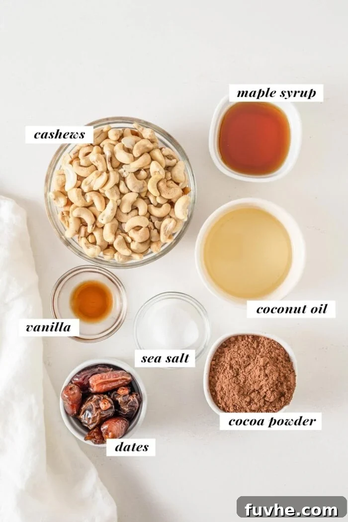 Overhead view of meticulously labelled ingredients for crafting delicious cashew cookie dough bars, including raw cashews, soft pitted dates, pure maple syrup, melted coconut oil, unsweetened cocoa powder, vanilla extract, and a pinch of sea salt, all laid out on a rustic wooden board.