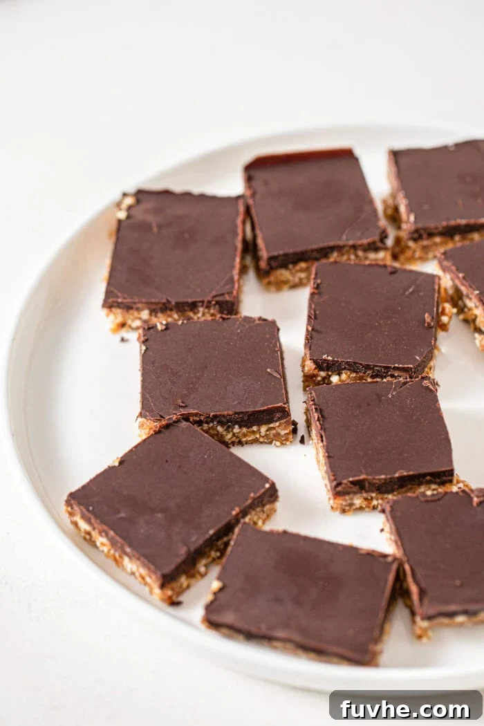 A plate showcasing 7 perfectly sliced chocolate-coated cashew cookie dough squares, arranged neatly. The edges are clean, and the distinction between the dark chocolate topping and the lighter cookie dough base is clear, ready for enjoyment.