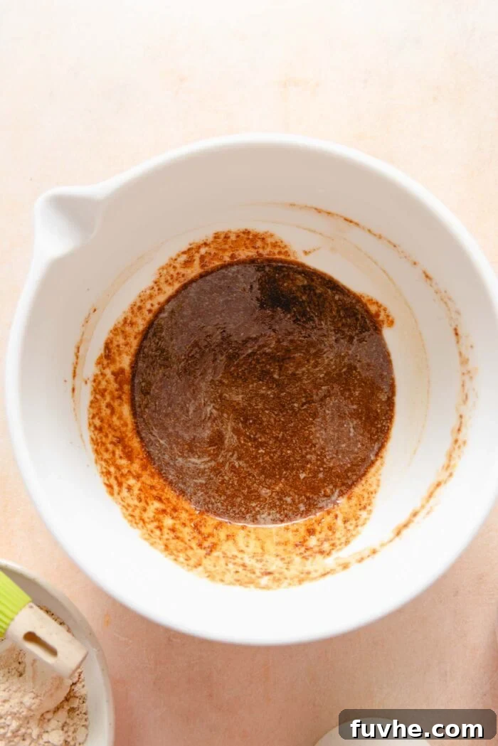 Scrumptious Peanut Powder Cookies 5 Coconut sugar, softened plant-based butter, prepared flax egg, and vanilla extract are being mixed together in a large bowl, forming a creamy, well-combined base.