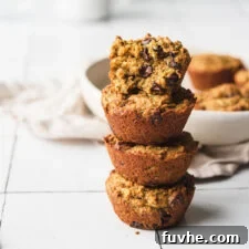 Protein-Powered Zucchini Muffins 11 Stack of four chocolate chip zucchini muffins. Muffin on top is cut in half to show inside texture, revealing moist texture and chocolate chips.