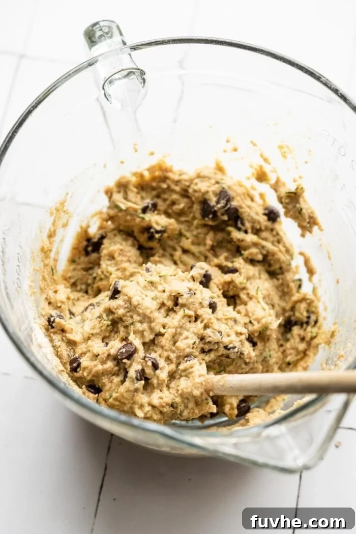 Protein-Powered Zucchini Muffins 7 Chocolate chip zucchini muffin batter mixed in a glass mixing bowl, showing the consistency before baking.