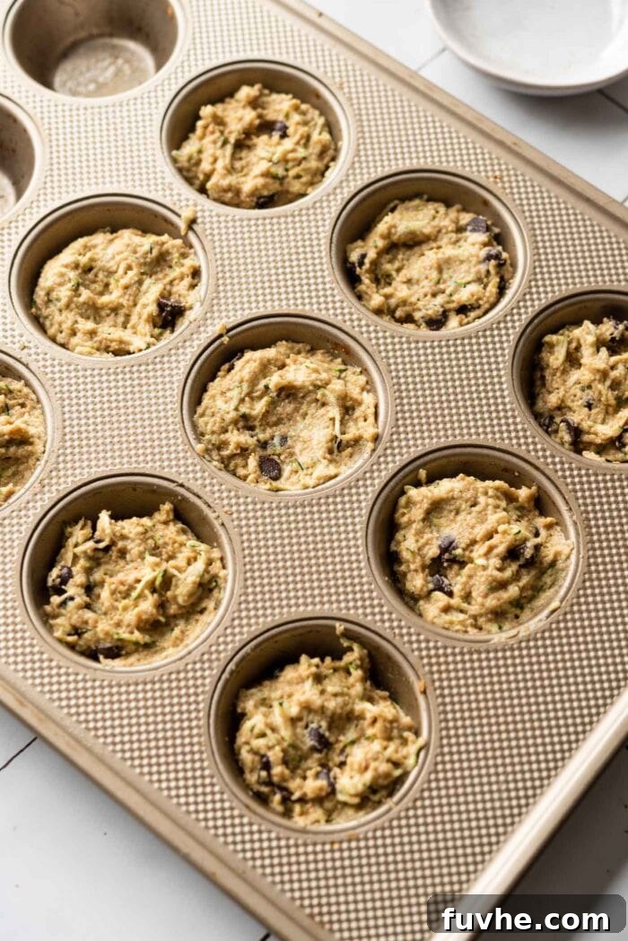 Protein-Powered Zucchini Muffins 8 Raw muffin batter scooped into a muffin pan, ready for baking.