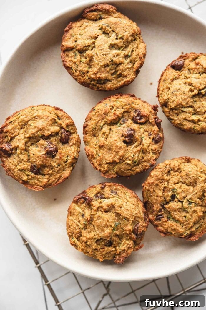Protein-Powered Zucchini Muffins 9 Freshly baked zucchini chocolate chip muffins cooling on a plate, showcasing their inviting texture.