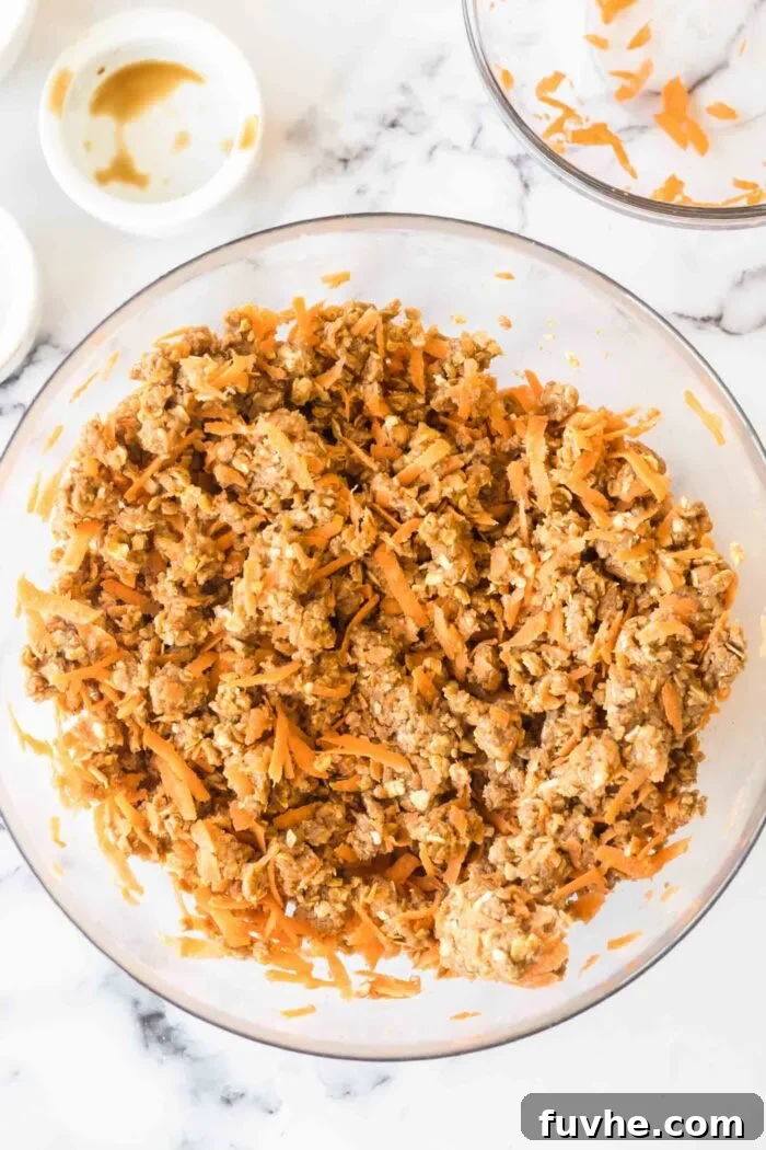 Carrot Cake Oatmeal Cookies 5 Crumbly carrot cake cookie dough with visible grated carrots and oats in a mixing bowl, ready for shaping.