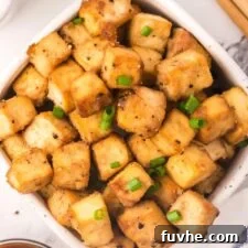 A big bowl of crispy baked tofu cubes sprinkled with green onion.