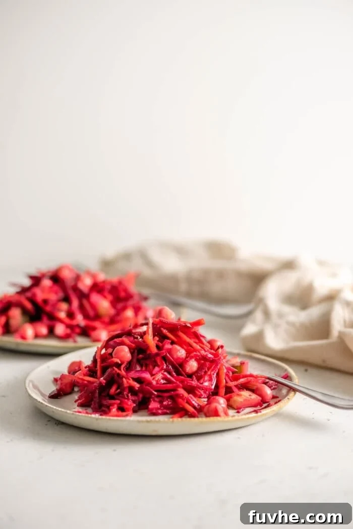 Two plates generously filled with the vibrant beet, chickpea, and carrot salad, ready to be enjoyed as a healthy and colorful meal.