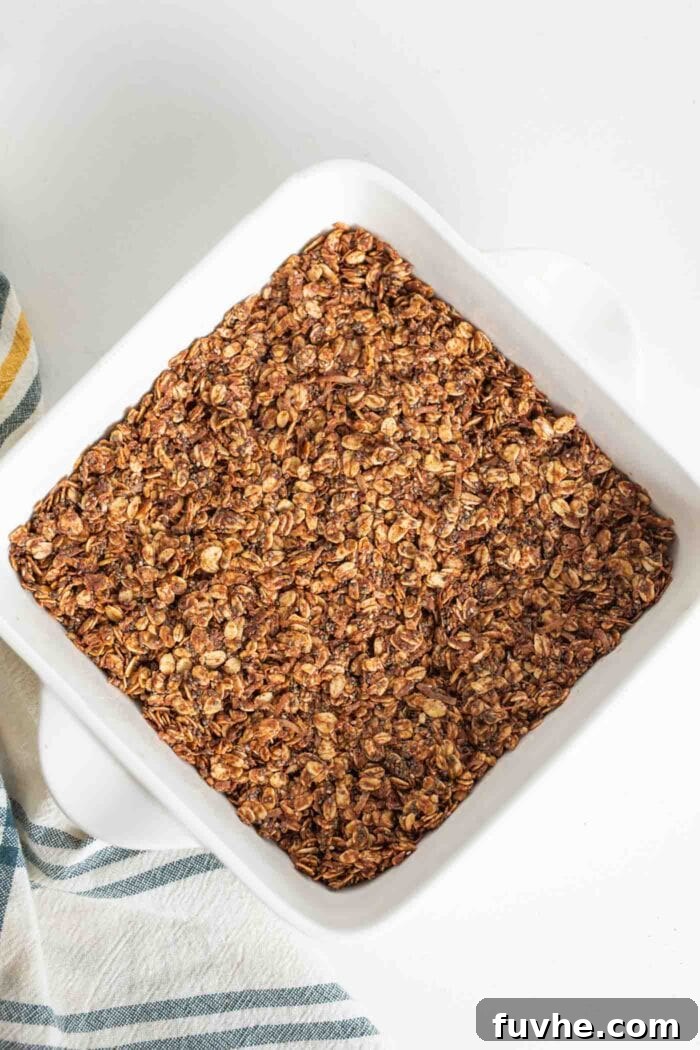 A freshly pressed layer of chocolate oat bars mixture nestled in a baking dish, ready for chilling.