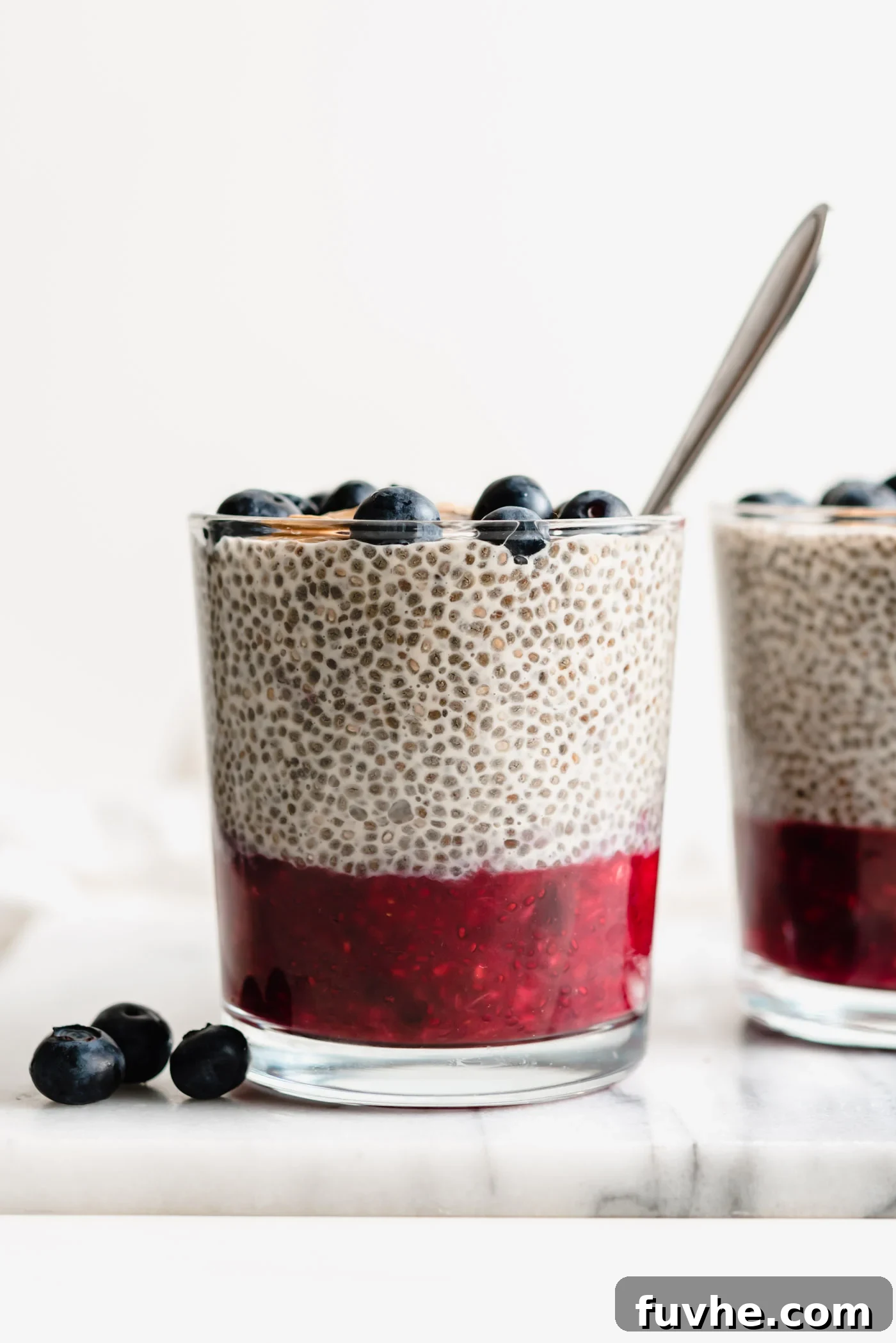 Peanut Butter Jelly Chia Bliss 2 Two elegant glass jars filled with peanut butter chia pudding, topped with a rich layer of berry jam and fresh berries.