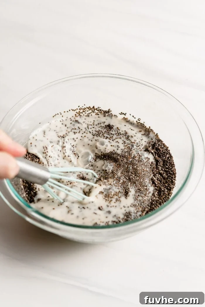 Peanut Butter Jelly Chia Bliss 3 A person whisking together milk and chia seeds in a bowl to form the pudding base.