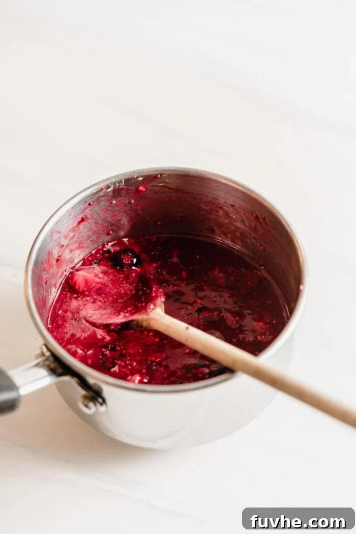 Peanut Butter Jelly Chia Bliss 4 Mashing cooked berries in a small pot to create a compote.