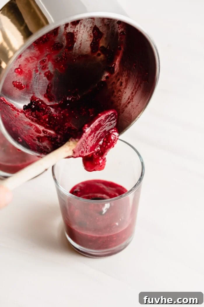 Peanut Butter Jelly Chia Bliss 5 Pouring the homemade berry compote from a pot into a small glass jar.