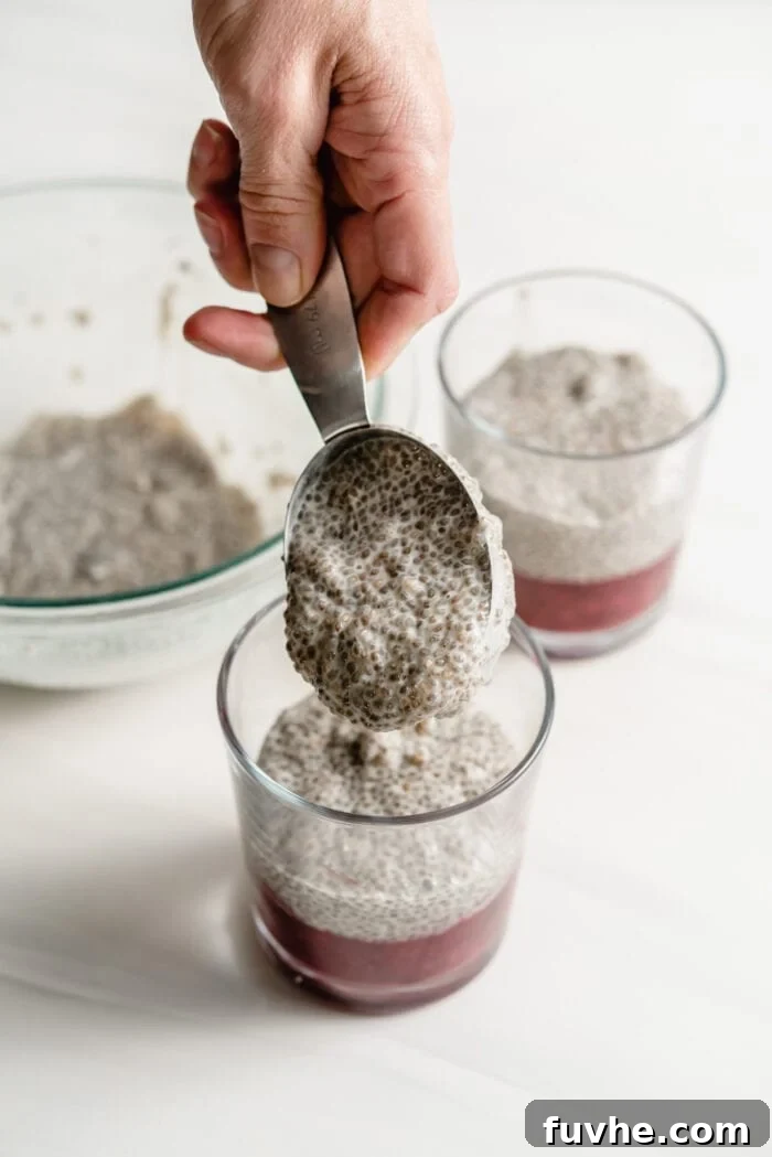 Peanut Butter Jelly Chia Bliss 6 Adding a scoop of creamy chia pudding to the berry compote in small glass jars for layering.