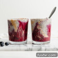 Two jars of peanut butter chia pudding with a layer of jam on the bottom of the jars, ready to be served.