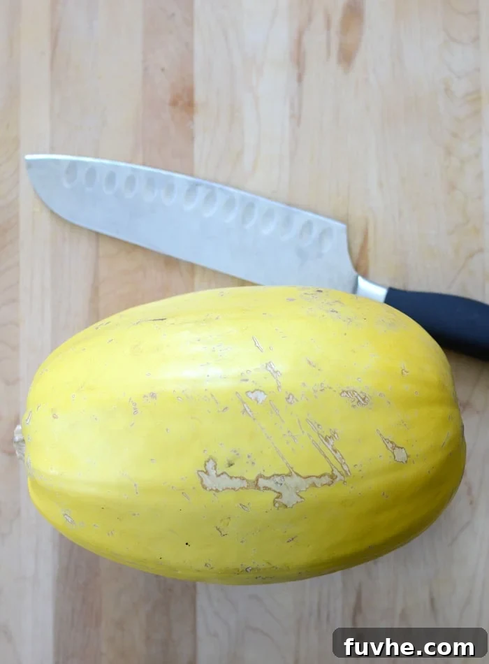 Spaghetti Squash on a cutting board with a large, sharp knife beside it, illustrating the preparation stage.