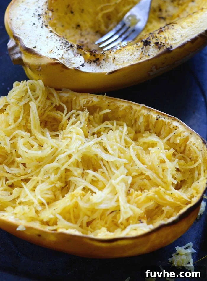 A fork being used to scrape the cooked flesh of a spaghetti squash into delicate, spaghetti-like strands.