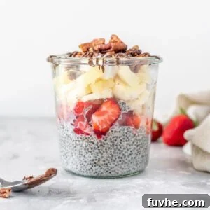 A jar of chia pudding topped with strawberries, banana, pecans and chocolate sauce, presenting a healthy banana split alternative.