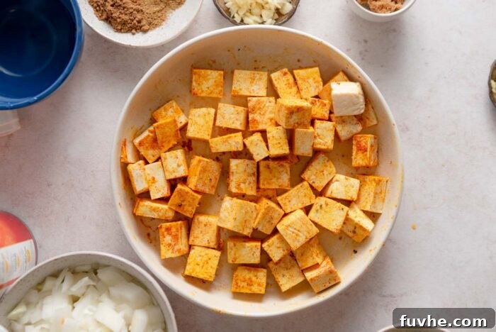 Cubes of tofu coated in turmeric and paprika in a bowl.