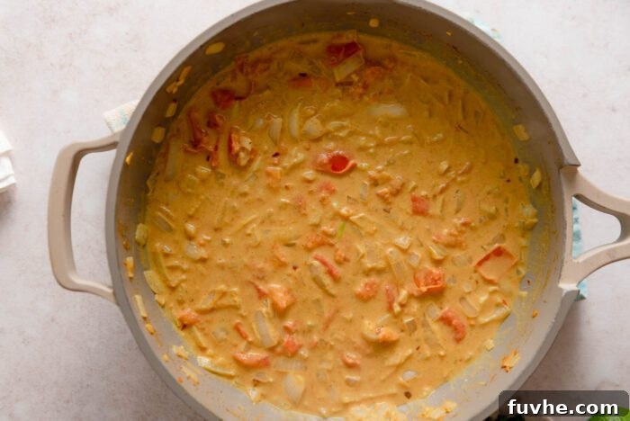 Diced tomato and onion cooking in a creamy coconut curry sauce.