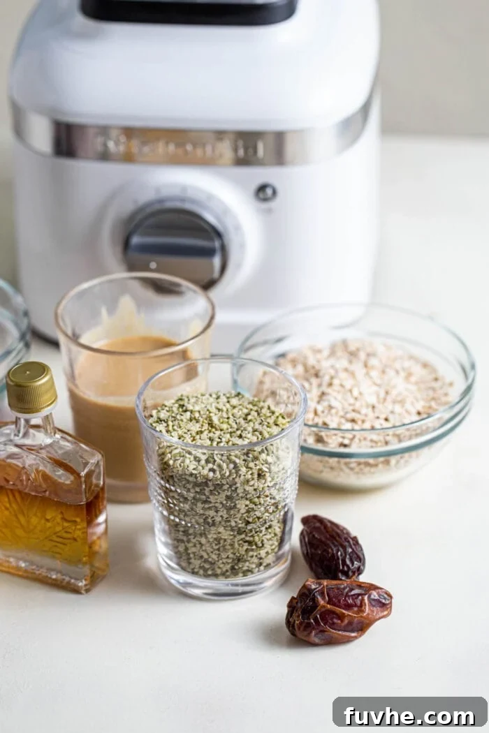 Various whole-food ingredients including hemp seeds, tahini, shredded coconut, soft dates, and maple syrup arranged on a countertop, ready for baking.