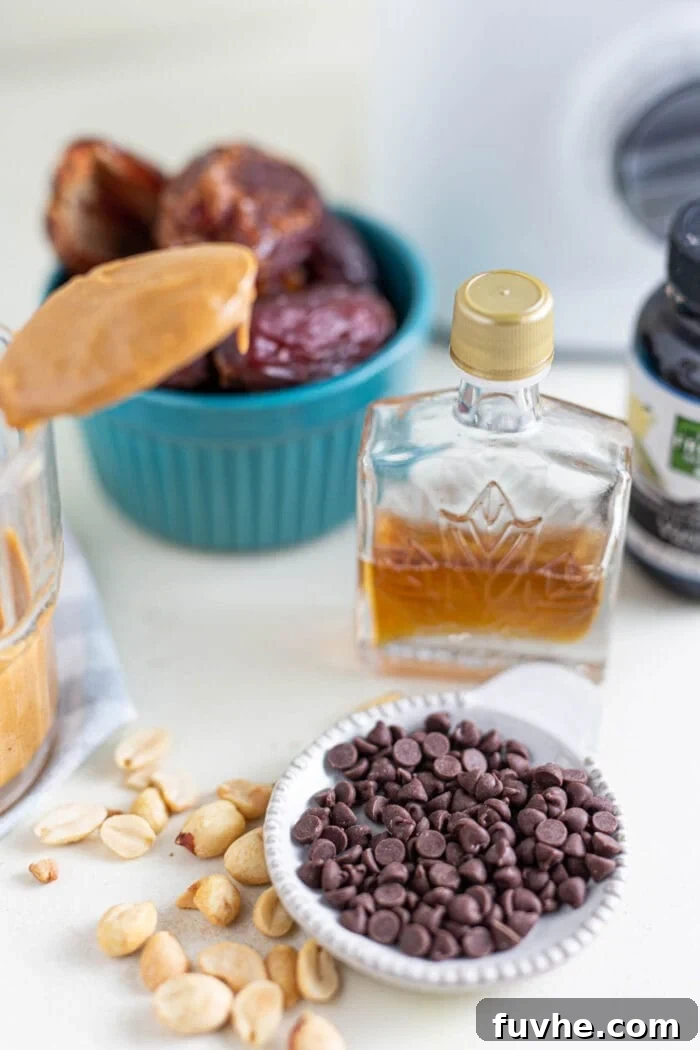 Containers holding dairy-free chocolate chips, golden maple syrup, and pitted dates arranged on a clean white surface.