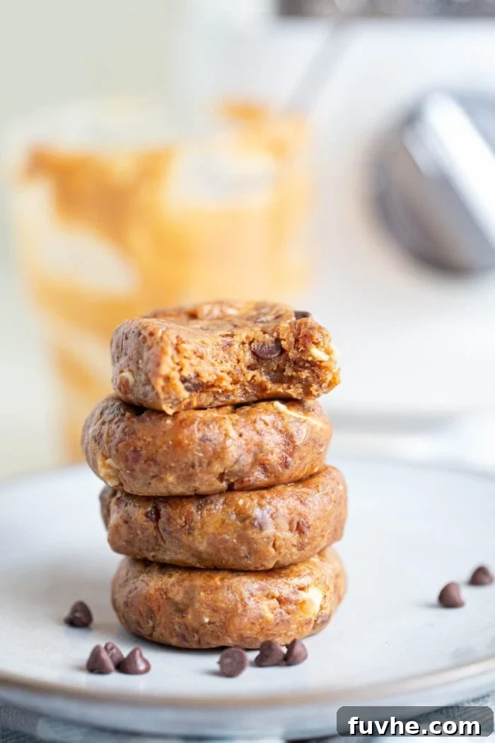 A perfectly stacked pile of four no-bake peanut butter chocolate chip cookies on a pristine white plate, ready to be served.