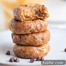 A stack of four raw peanut butter cookies with a scattering of chocolate chips, emphasizing their simple beauty.