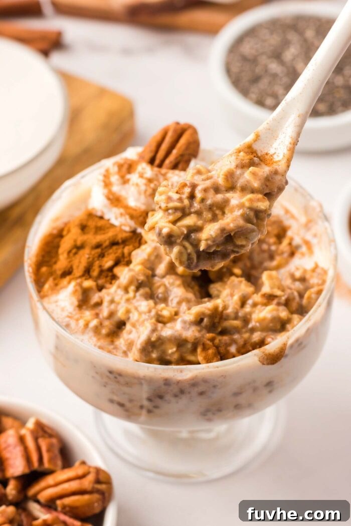 Spiced Pumpkin Overnight Oats 7 A spoon scooping pumpkin overnight oats from a bowl. The oats are topped with cinnamon and a pecan.