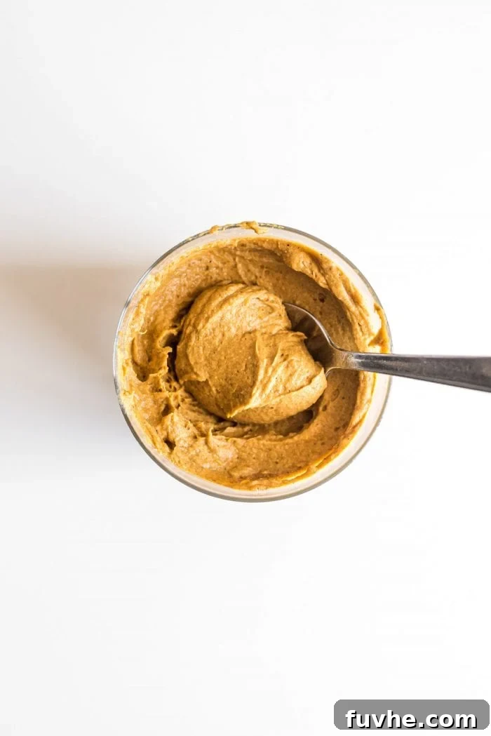 Pumpkin Power Pudding 2 Vegan pumpkin pie protein pudding in a glass jar being scooped with a spoon.