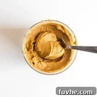 Pumpkin Power Pudding 5 Vegan pumpkin pie protein pudding in a glass jar being scooped with a spoon.