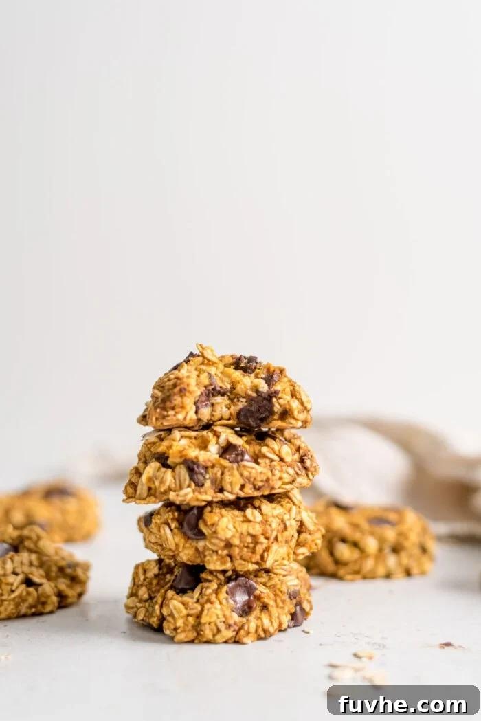 A stack of golden-brown pumpkin chocolate chip cookies, with a bite taken out of the top one, revealing the soft interior.