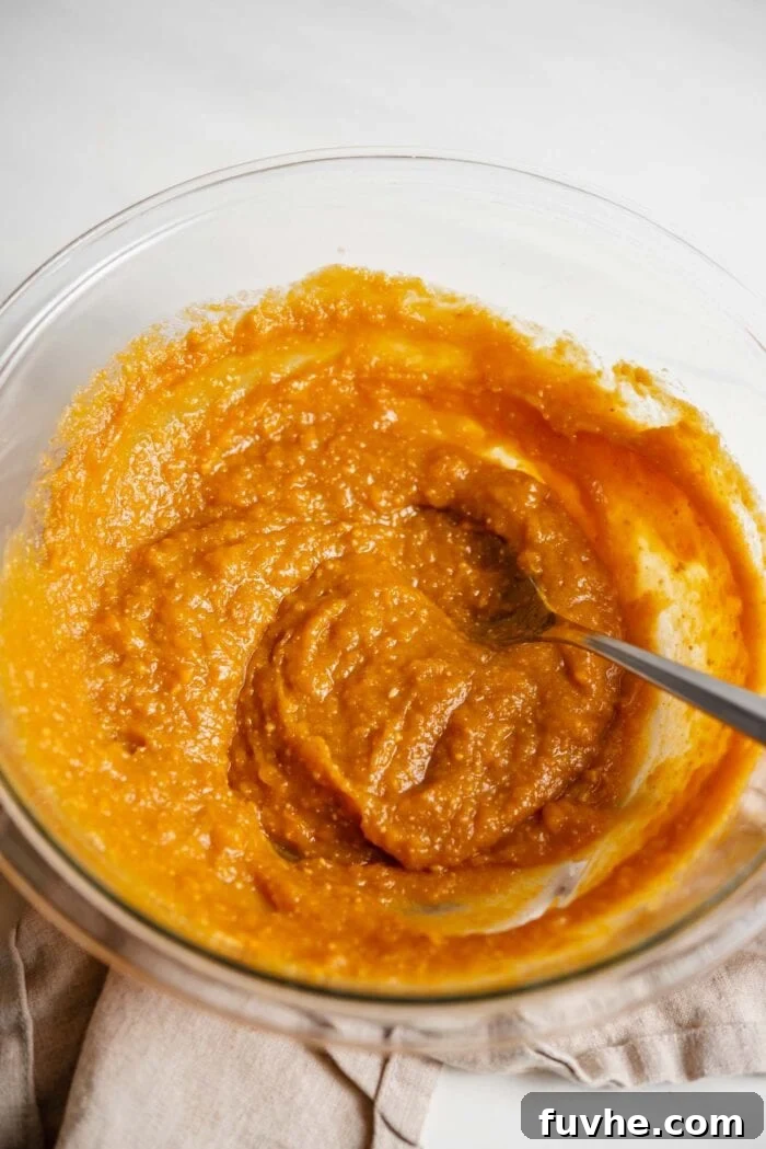 Sweet Potato Spice Cookies 4 A creamy sweet potato mixture in a glass mixing bowl with a spoon, showing the consistency of the wet ingredients.