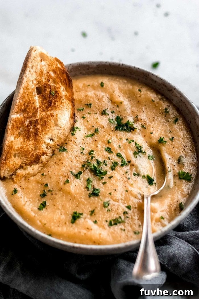 Golden Roasted Garlic Cauliflower Soup 9 Creamy roasted garlic cauliflower soup in a beautifully styled bowl with fresh parsley and slices of toasted bread.