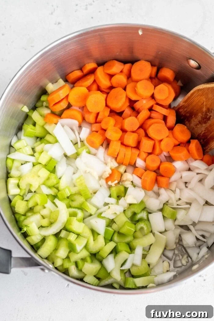 Velvety Cauliflower Potato Comfort 4 Finely diced onions, carrots, celery, and minced garlic are gently sautéing in a soup pot, stirred with a wooden spoon, forming the aromatic base for the soup.