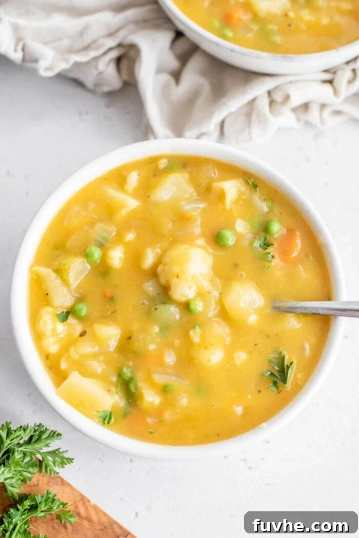 Velvety Cauliflower Potato Comfort 10 A charming bowl of creamy cauliflower and potato soup, studded with vibrant green peas, beckoning with its wholesome goodness.