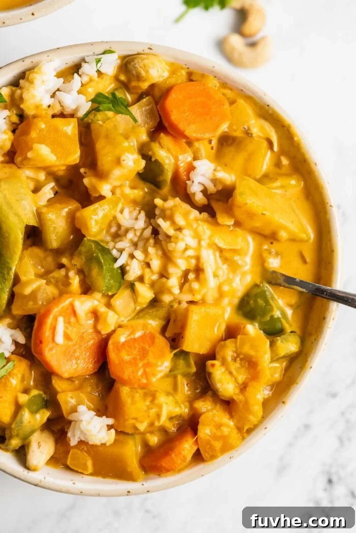 Spiced Kabocha Delight 9 A beautifully presented bowl of red squash curry, brimming with bell peppers and carrots, served over rice and elegantly topped with fresh cilantro leaves.