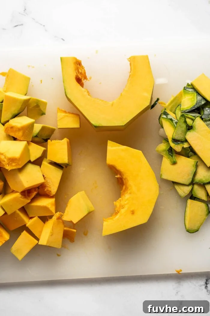 Silken Kabocha Squash Soup 5 Neatly arranged wedges of kabocha squash, peeled and cut into uniform cubes, await cooking on a wooden cutting board.