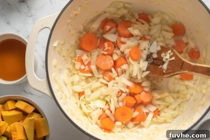Silken Kabocha Squash Soup 6 Diced onions, minced garlic, fresh ginger, and chopped carrots are actively sautéing in a large soup pot with a wooden spoon, releasing their fragrant aromas.