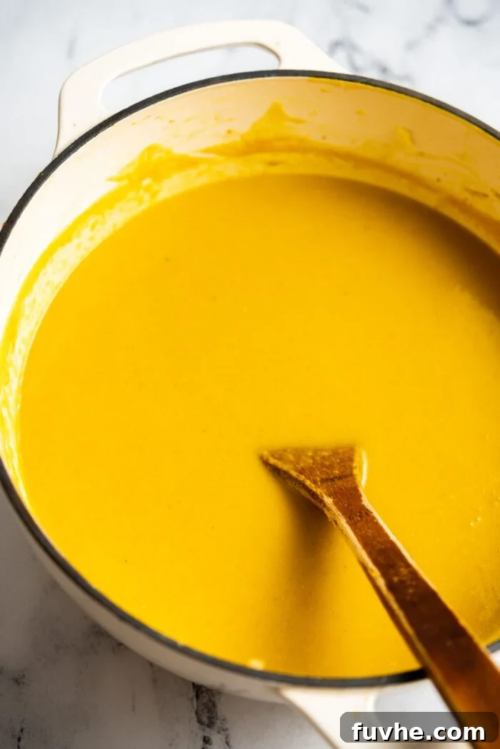 Silken Kabocha Squash Soup 10 A large pot filled with the velvety smooth, creamy kabocha squash soup, with a wooden spoon resting inside, ready to be served.