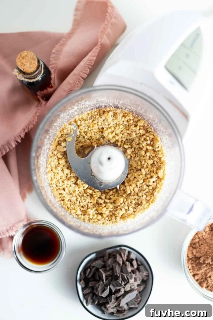 Blended raw walnuts forming a coarse flour in a food processor bowl.