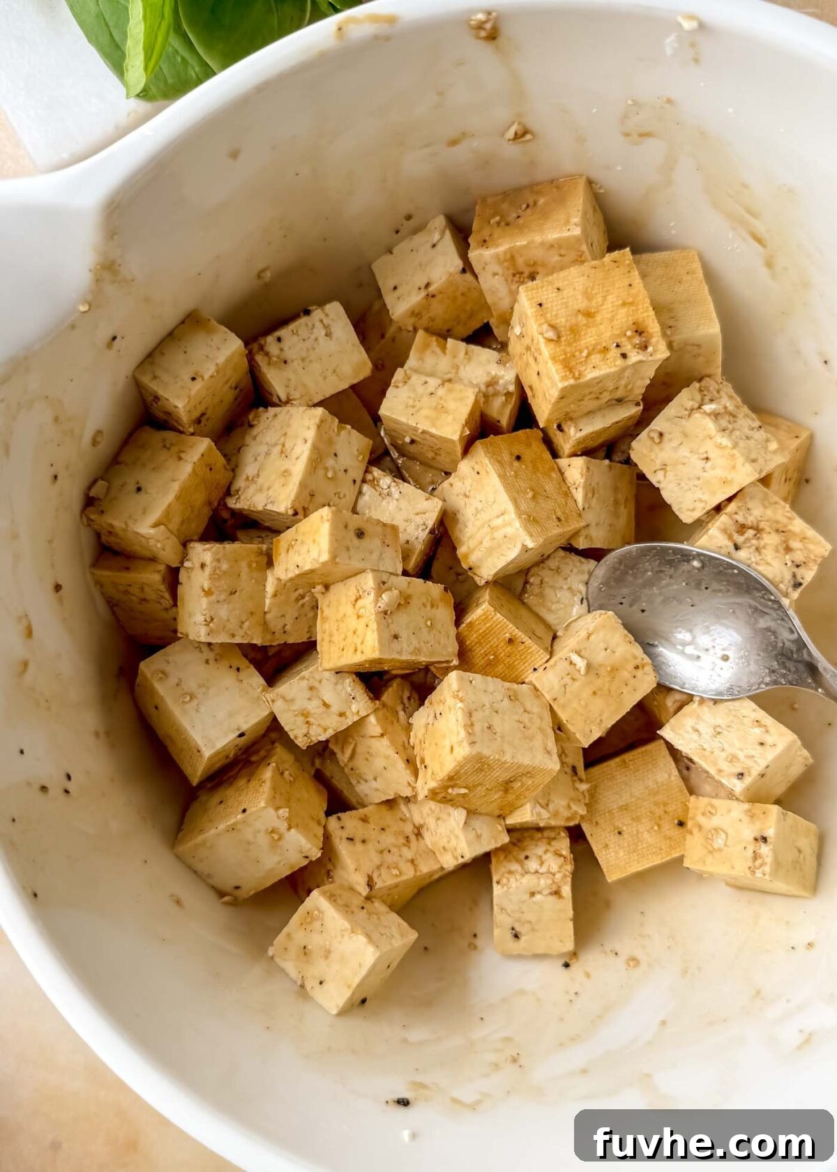 Umami Tofu Soba Bowl 4 Cubed tofu coated in a light brown marinade inside a white mixing bowl before cooking, showing a beautiful, even seasoning on each piece.