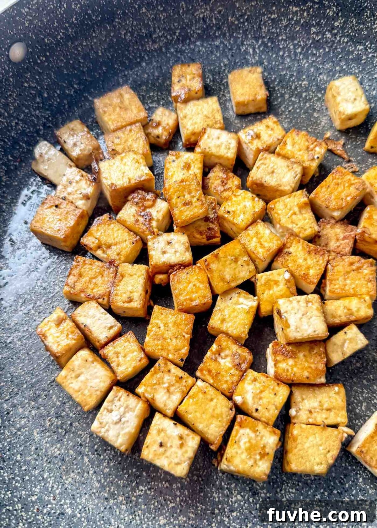 Umami Tofu Soba Bowl 6 Golden, crispy tofu cubes browning beautifully in a nonstick skillet, with lightly caramelized edges indicating perfect crispiness.