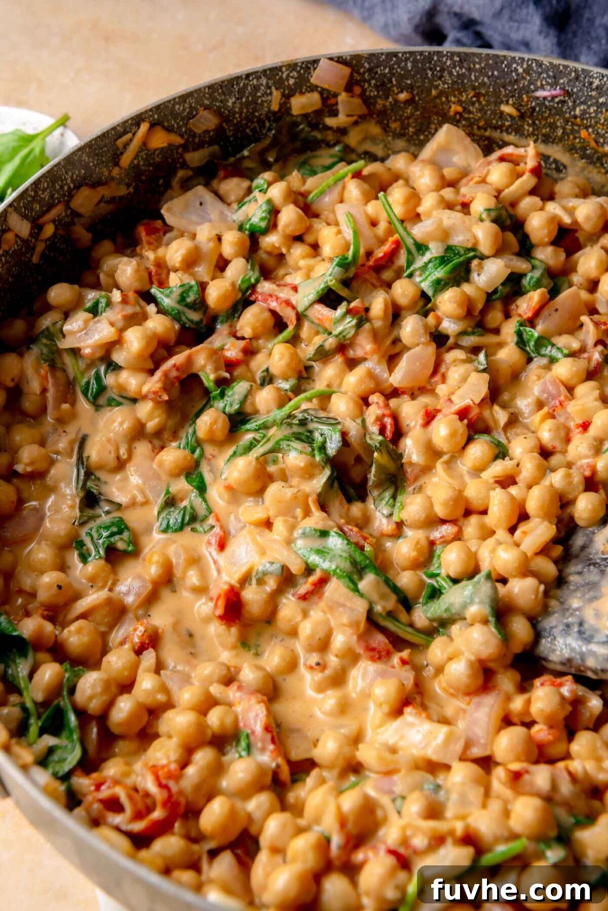 Head Over Heels for Chickpeas 8 Creamy chickpea sauce simmering in a skillet with sun-dried tomatoes and wilted spinach, showing a thick, glossy texture.