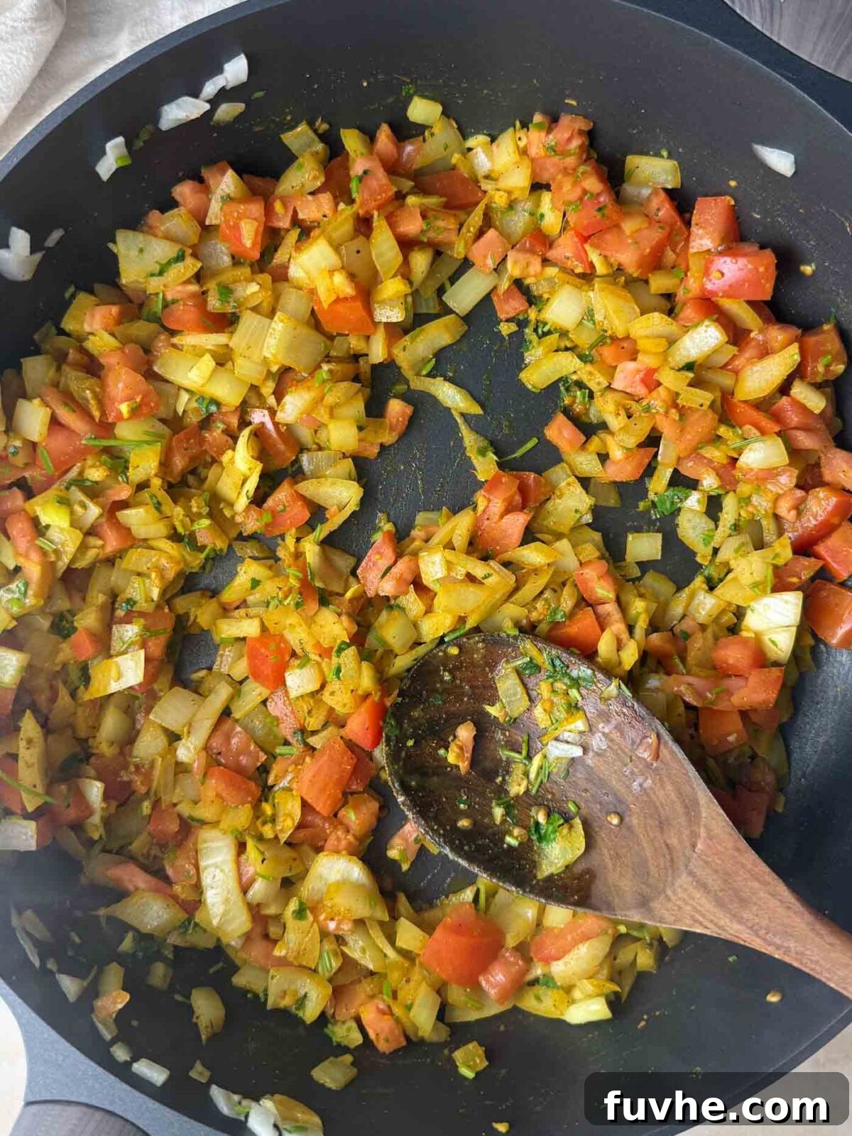 Onions and tomato coated in turmeric and warm spices as they toast in oil.