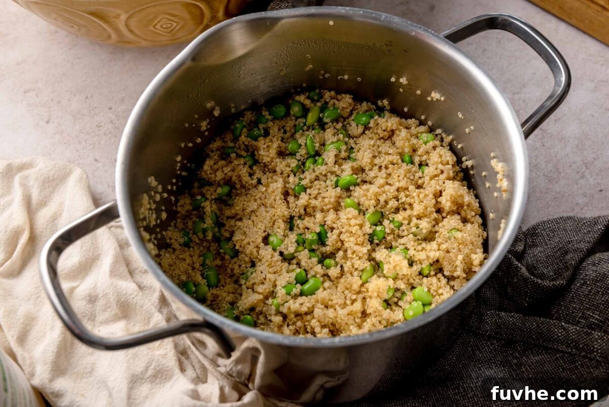 Cooked quinoa with edamame in a saucepan, light and fluffy grains mixed with bright green soybeans.