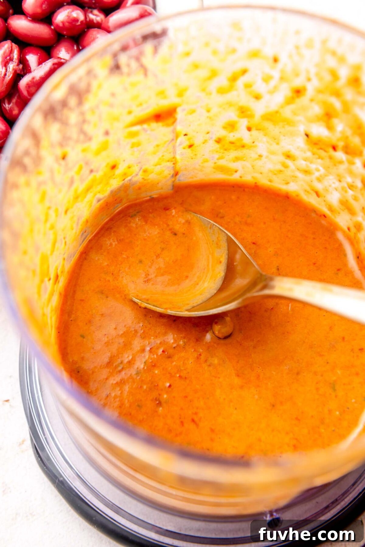 Creamy, vibrant chipotle cilantro dressing in a small food processor cup with a spoon, showing its smooth consistency.