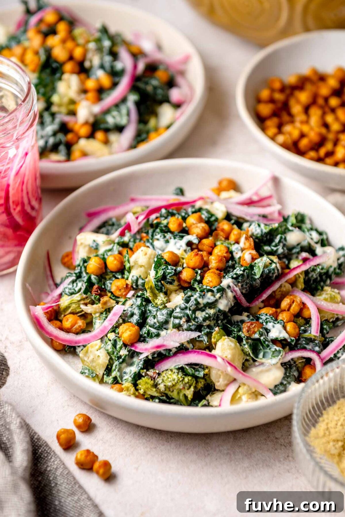 Golden Roasted Vegetable Caesar 2 Roasted vegetable Caesar salad with crispy chickpeas, kale, broccoli, cauliflower, and pickled red onions in a creamy dressing, served in a shallow bowl. A vibrant and healthy meal.
