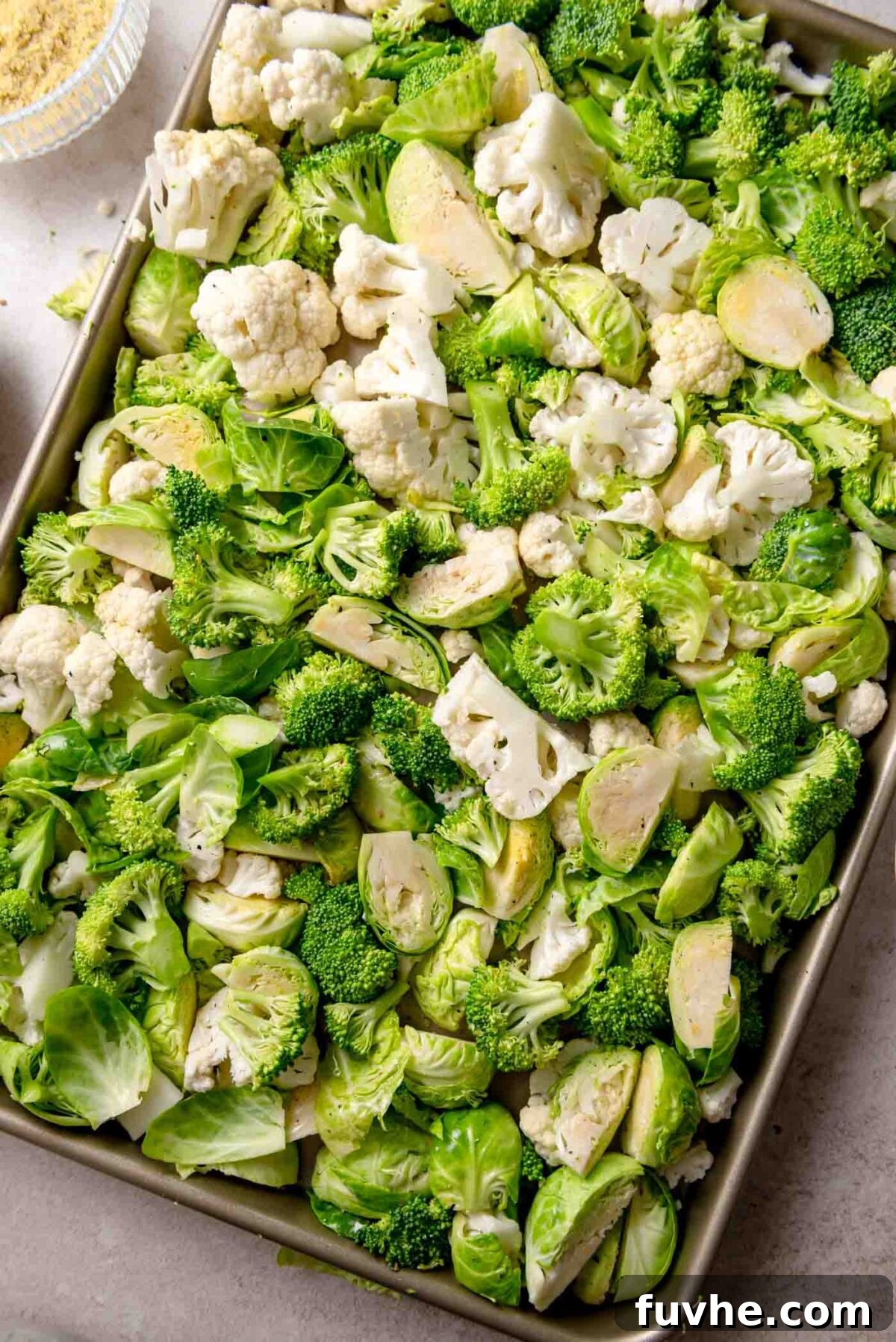 Golden Roasted Vegetable Caesar 5 Sheet pan of raw broccoli, cauliflower, and Brussels sprouts prepared for roasting, seasoned with salt, pepper, and olive oil.